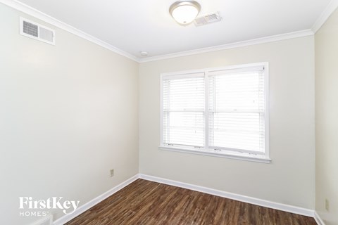 a bedroom with white walls and wood flooring and a window