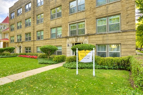 an apartment building with a sign in front of a lawn