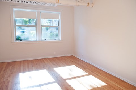 an empty room with wooden floors and a window