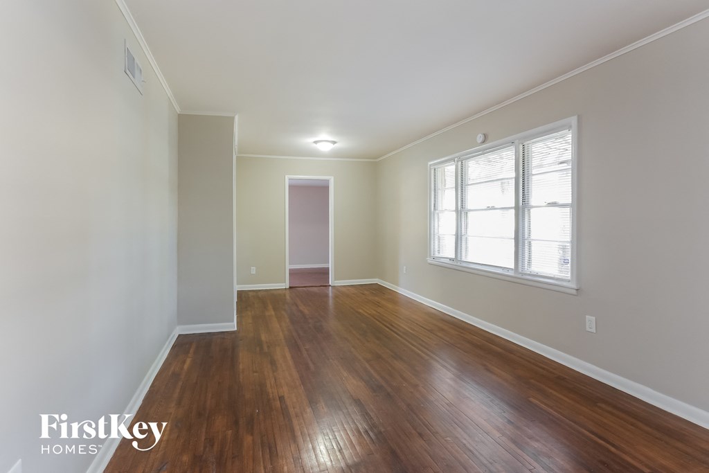 the living room of an empty house with wood flooring and a window