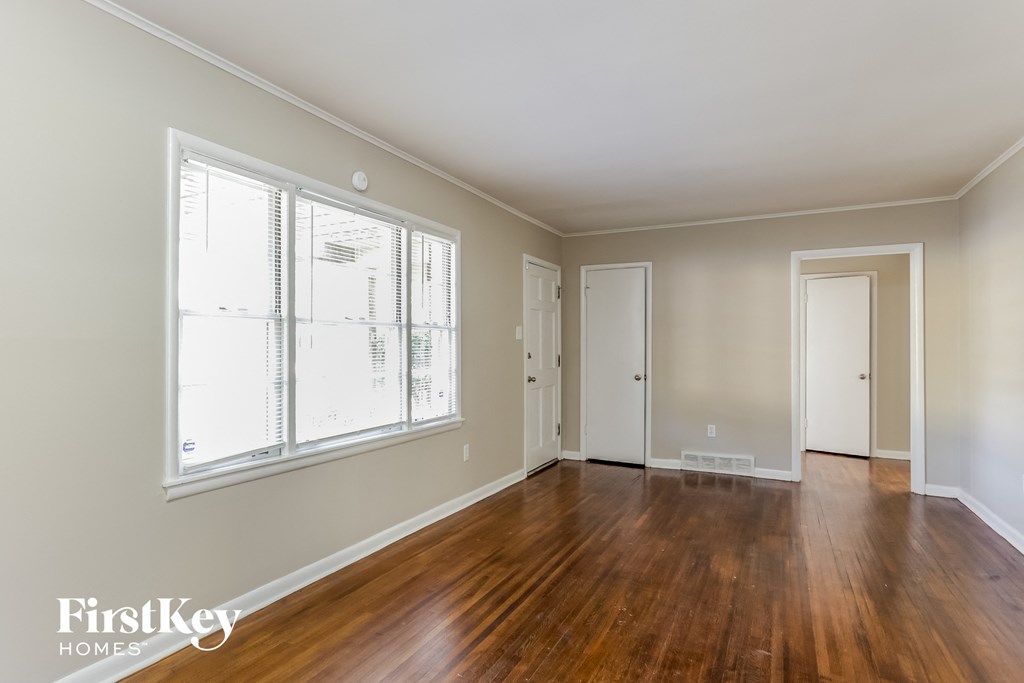 an empty living room with wood floors and a large window