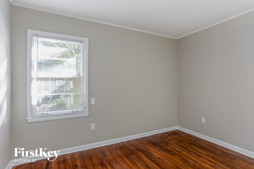 a bedroom with a window and wooden floors