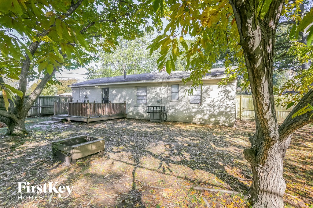a small white house with a deck and trees