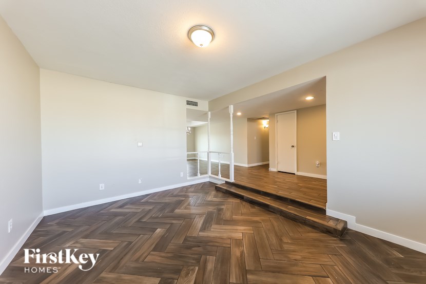 A spacious room with wooden flooring and a white ceiling.