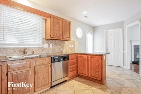 A kitchen with wooden cabinets and a stainless steel dishwasher.