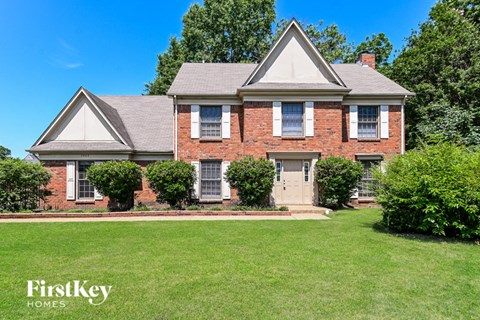 a brick house with white shutters and a lawn