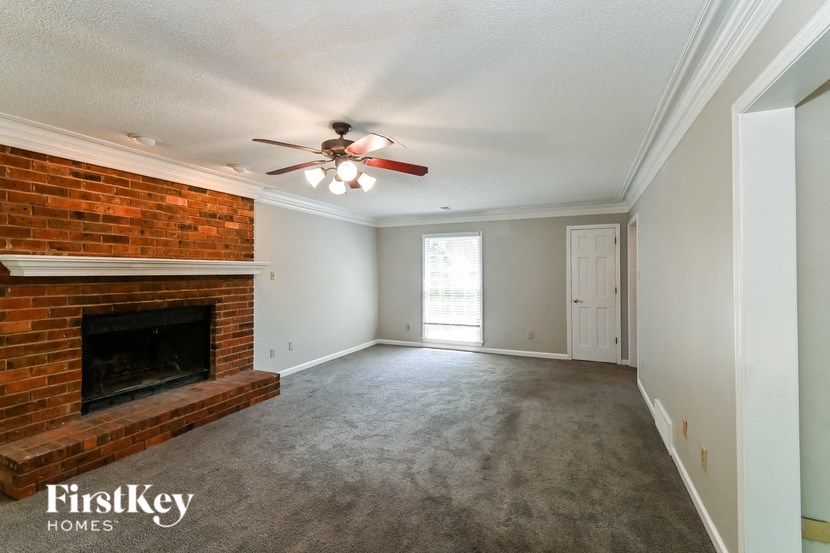 a living room with a brick fireplace and a ceiling fan