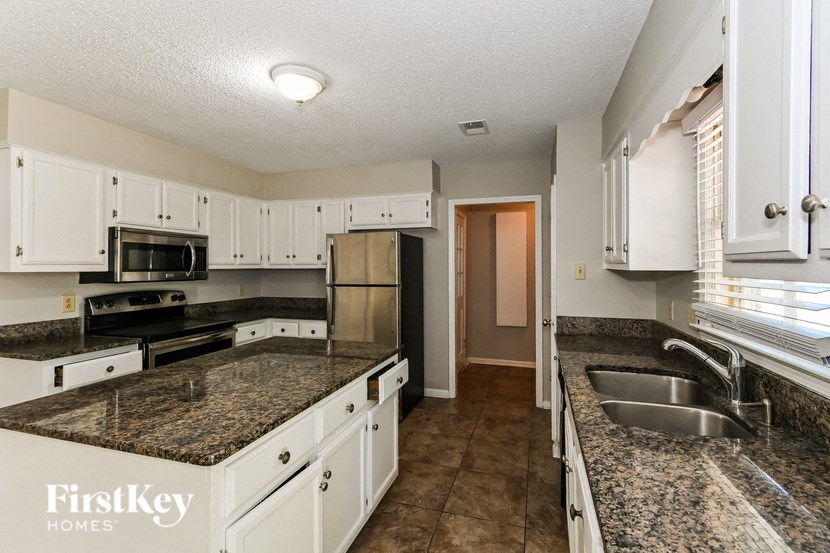 a kitchen with granite counter tops and white cabinets