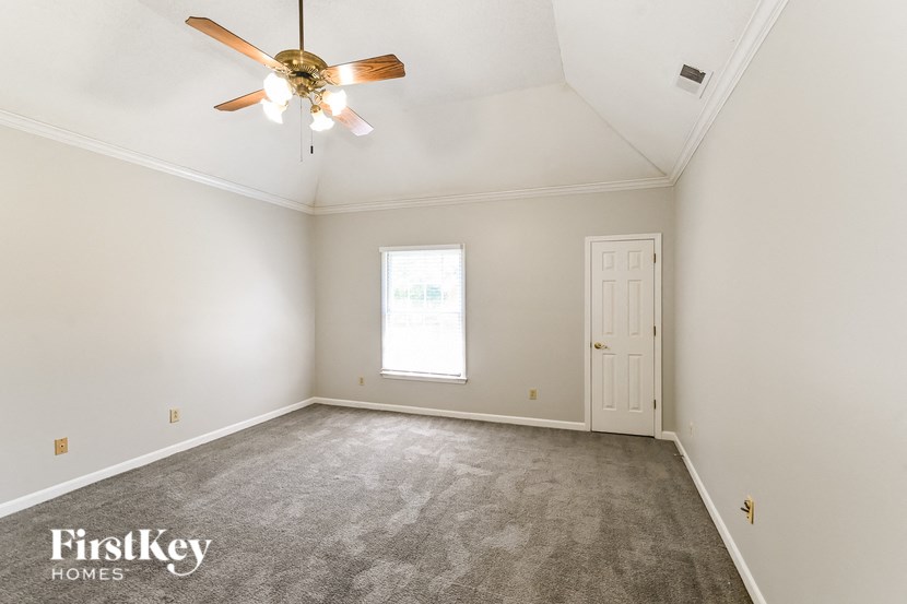 a bedroom with white walls and a ceiling fan and a white door