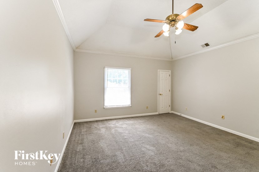 a living room with a ceiling fan and a carpet
