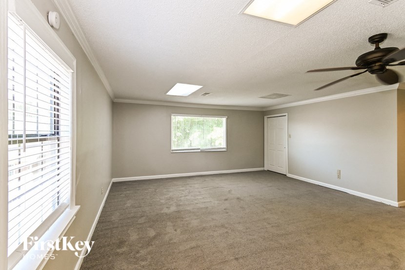 an empty living room with a ceiling fan and a window