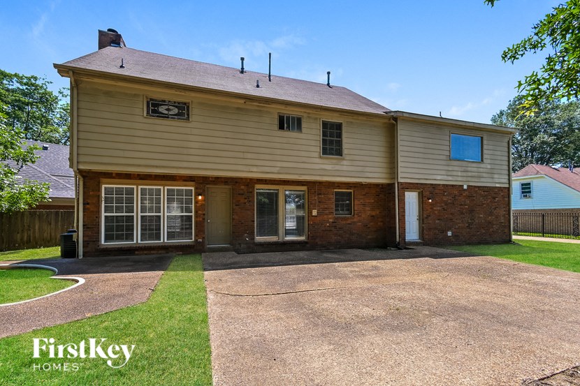 a home with a gravel driveway and a white and brown house