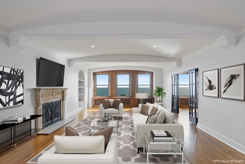 the living room has a fireplace and a view of the ocean