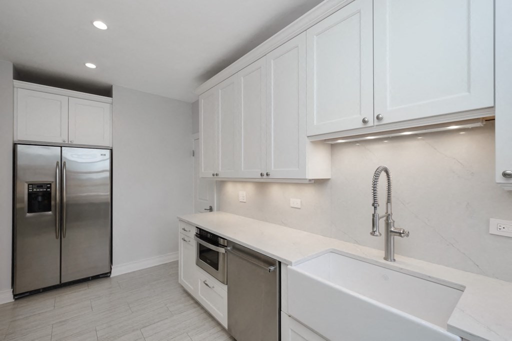 a kitchen with white cabinets and a stainless steel refrigerator