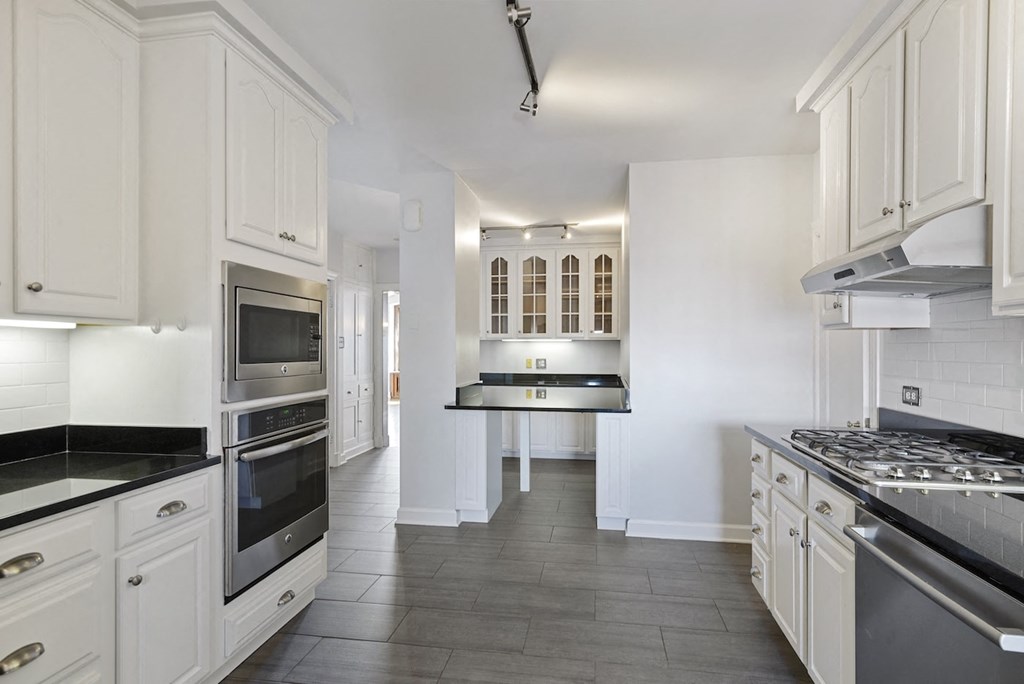 a white kitchen with stainless steel appliances and white cabinets