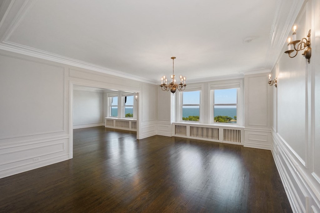 an empty living room with white walls and wood floors and a chandelier