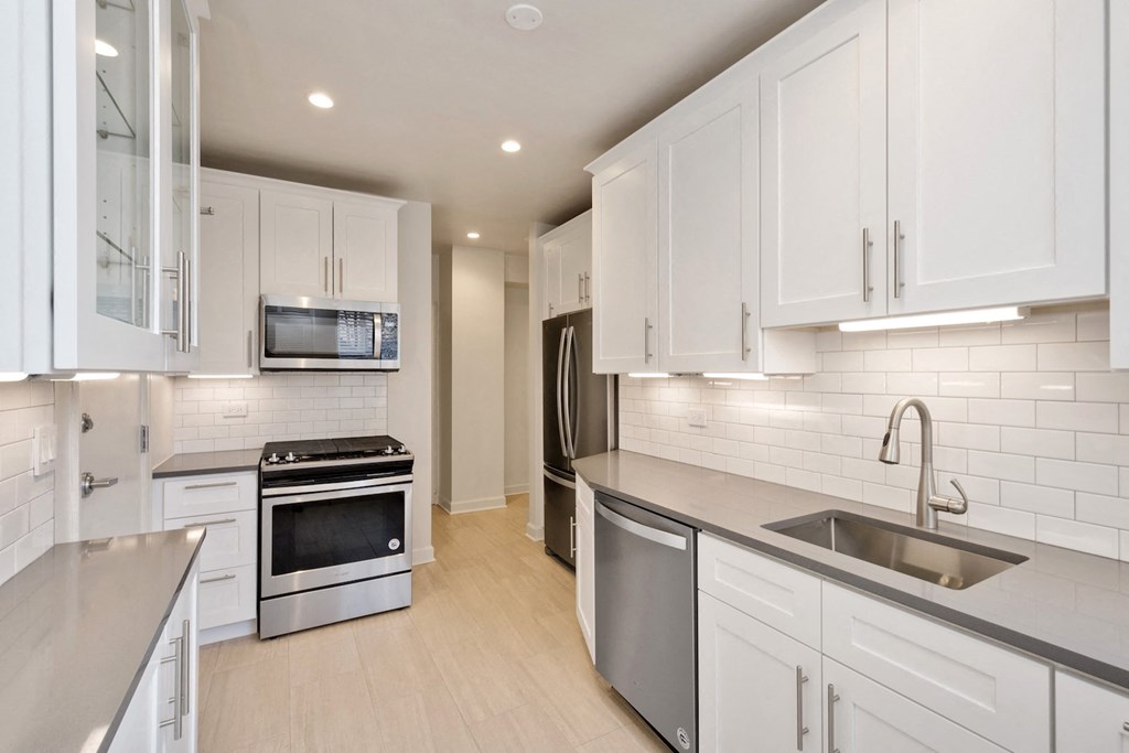 a white kitchen with stainless steel appliances and white cabinets
