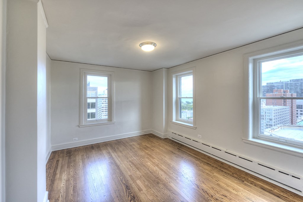 an empty living room with two windows and wood flooring