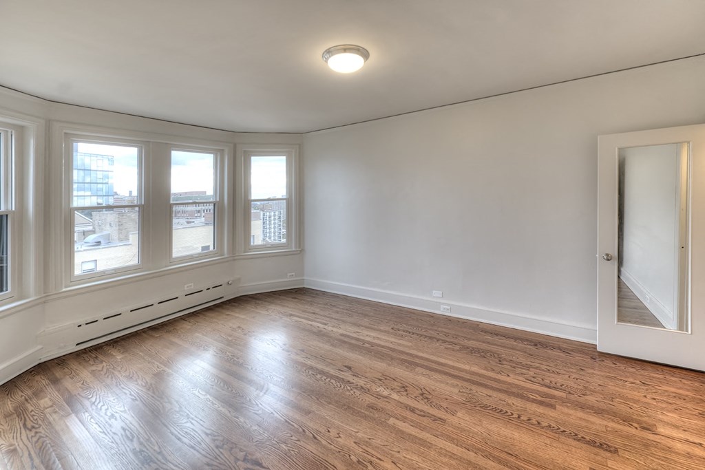 an empty living room with wood flooring and large windows