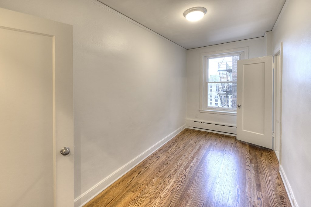 an empty living room with wood floors and a window