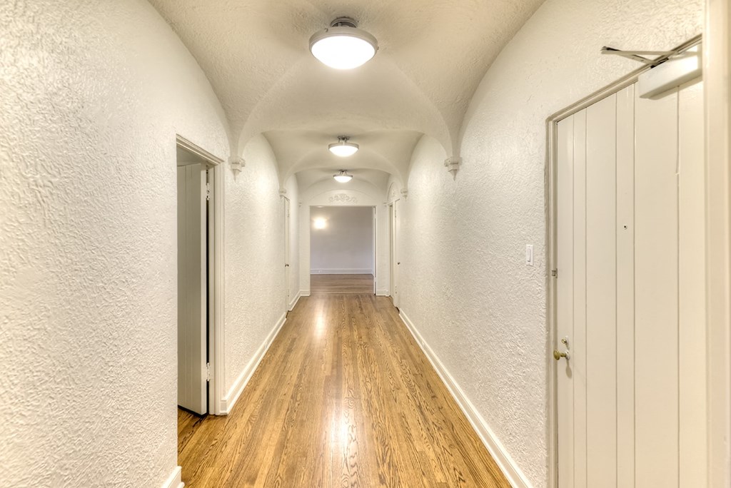 a long hallway with white walls and white doors and wood floors