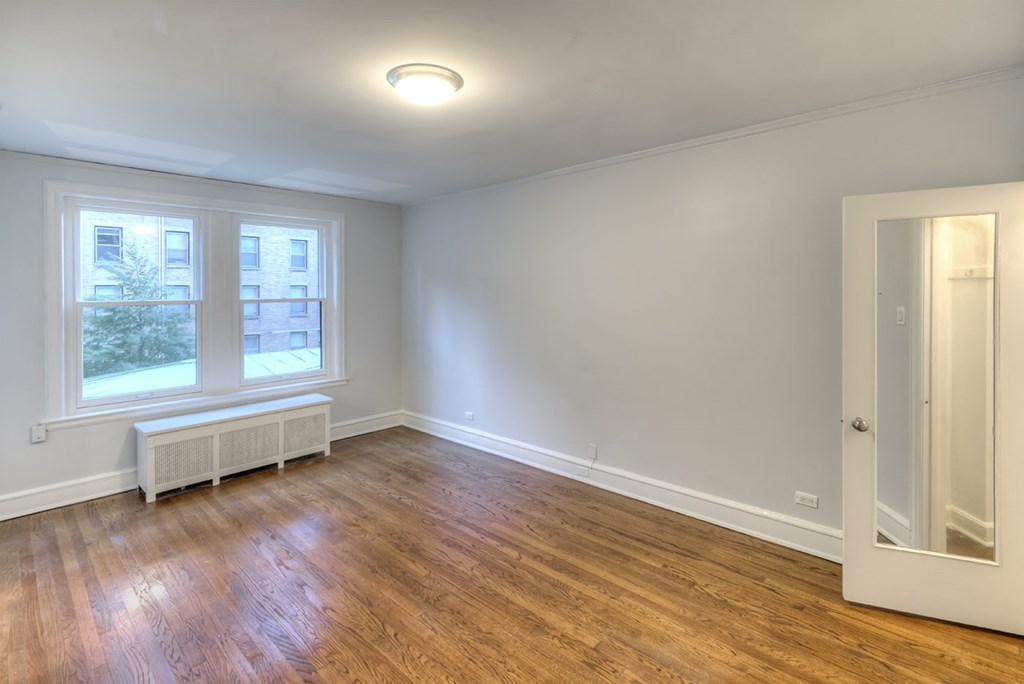 an empty living room with wood floors and a window