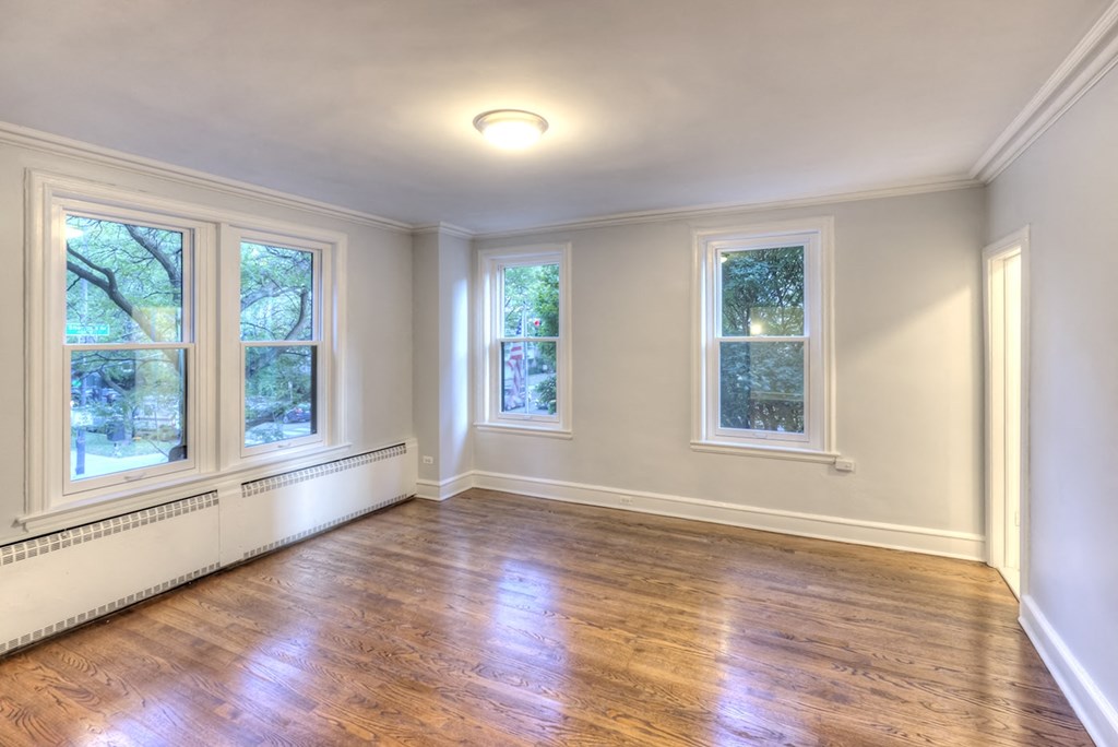 an empty living room with wood floors and three windows