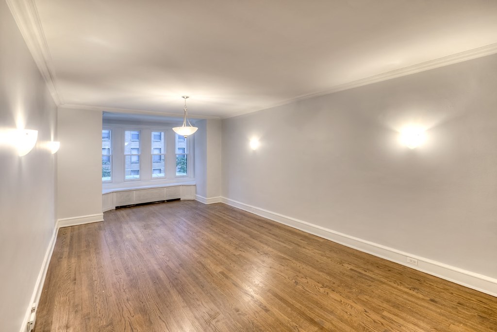 an empty living room with wood floors and a window
