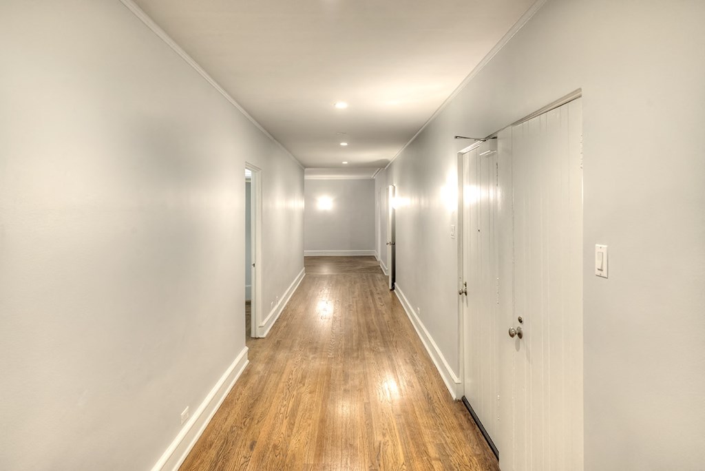 a hallway with white walls and wood floors and white closets