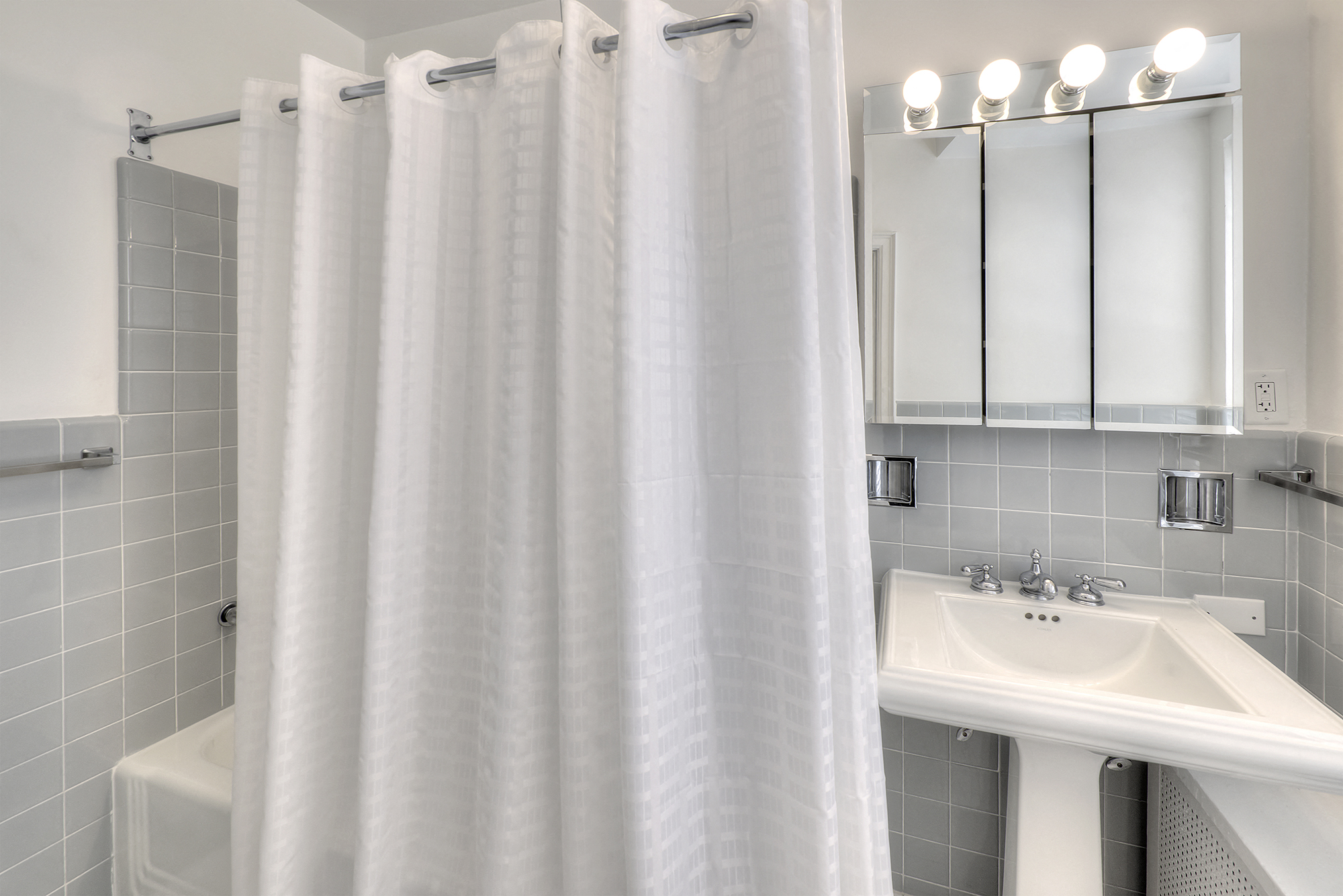 a white bathroom with a shower curtain and a sink