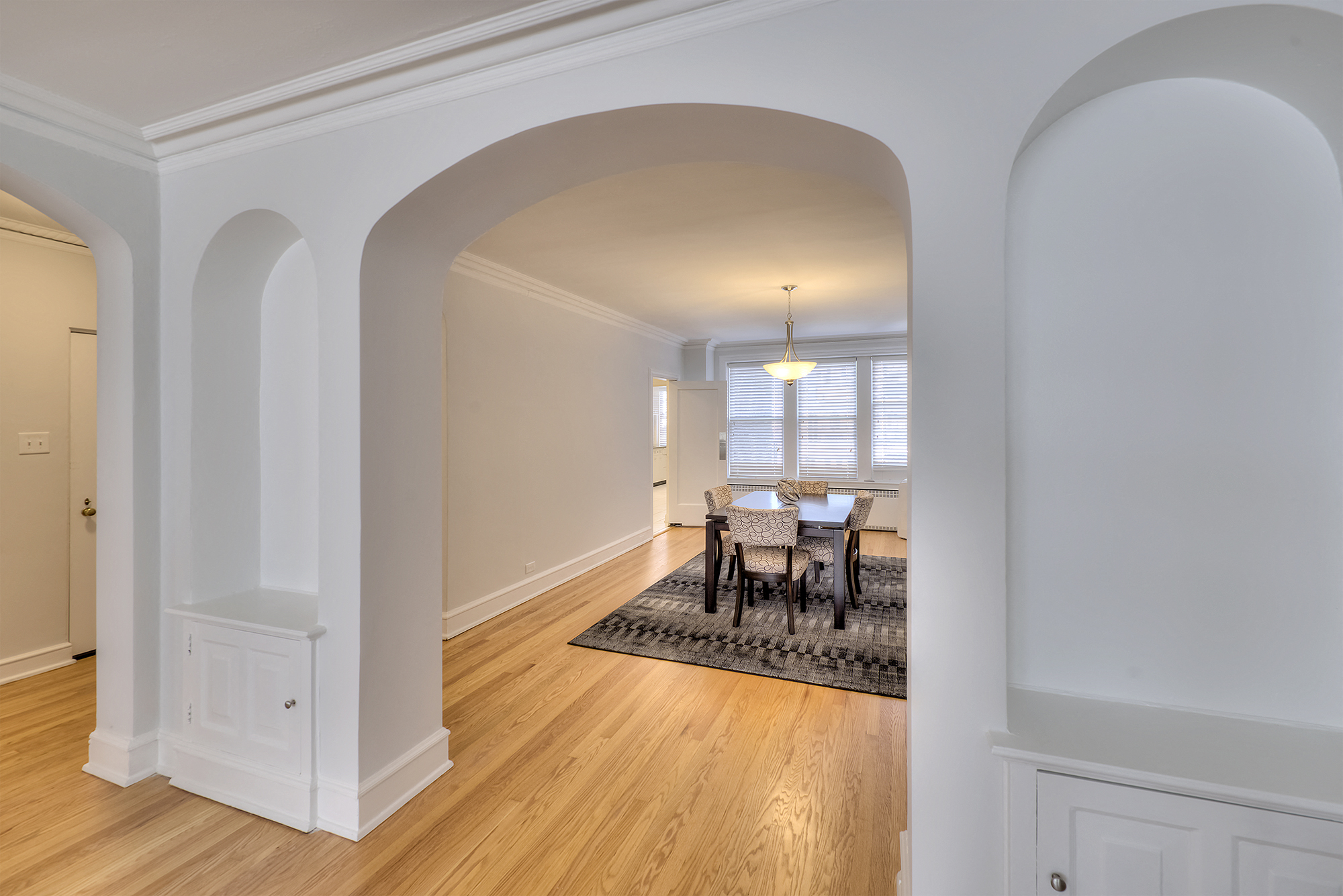 a living room and dining room with white walls and wood floors