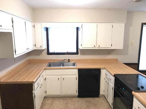 A kitchen with white cabinets and a wooden countertop.
