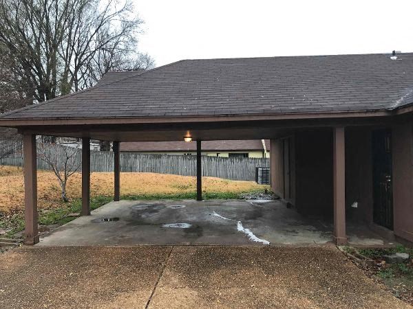 A covered patio area with a concrete floor and a brown roof.