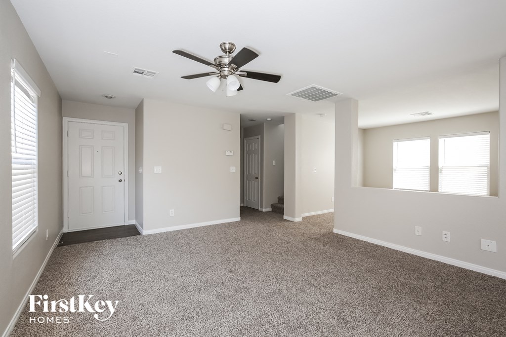 a empty living room with a ceiling fan and white walls