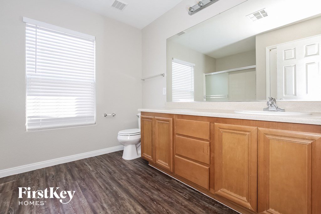 a bathroom with wooden cabinets and a toilet and a sink