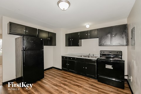 A kitchen with black appliances and wooden floors.