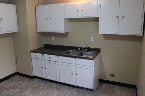 A kitchen with white cabinets and a black countertop.