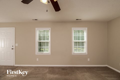 a empty room with two windows and a ceiling fan