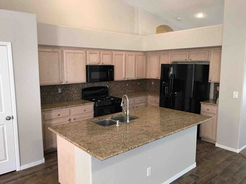 a kitchen with granite counter tops and white cabinets