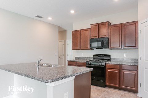 A kitchen with brown cabinets and a granite countertop.