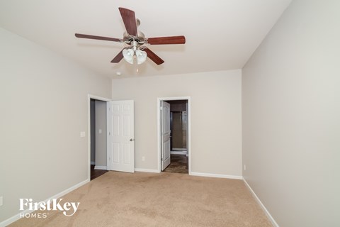 a living room with a ceiling fan and a carpet