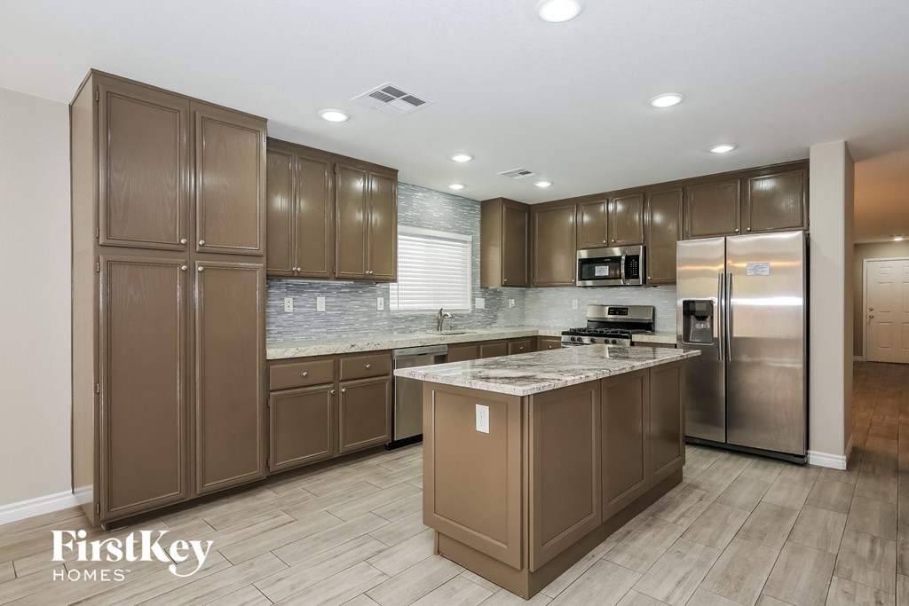 a large kitchen with stainless steel appliances and marble counter tops