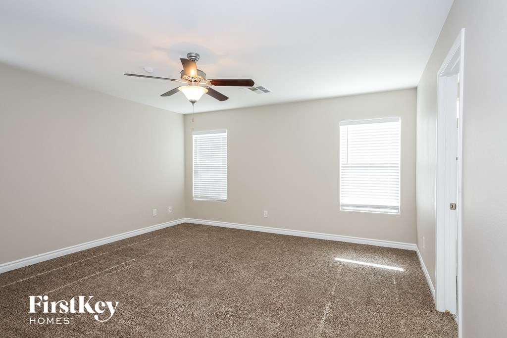 a bedroom with a ceiling fan and a carpeted floor