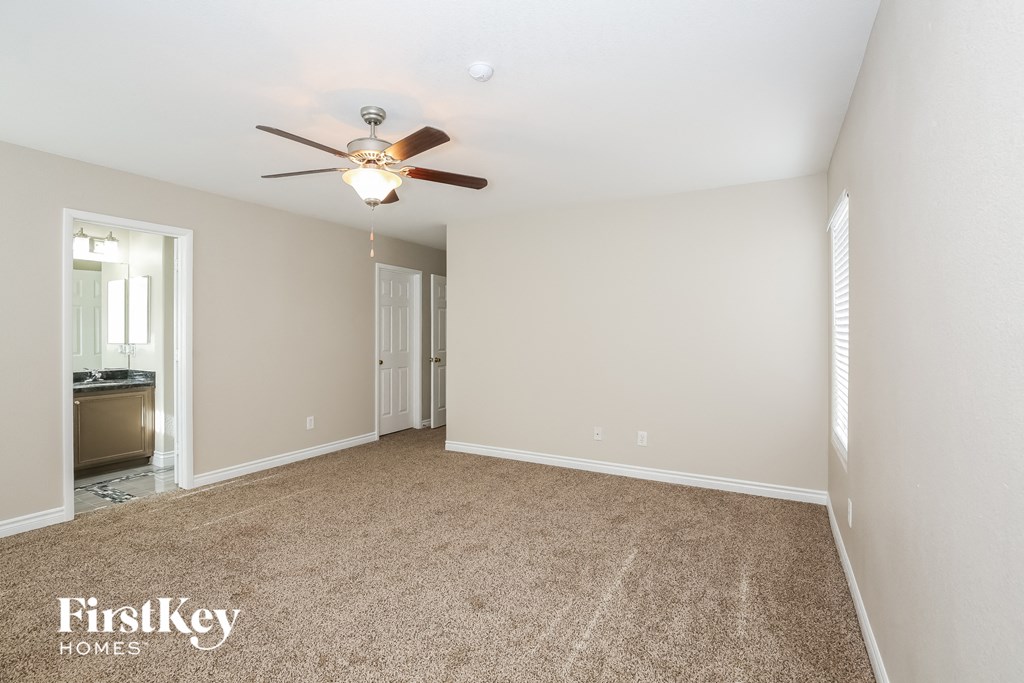 a spacious living room with carpet and a ceiling fan