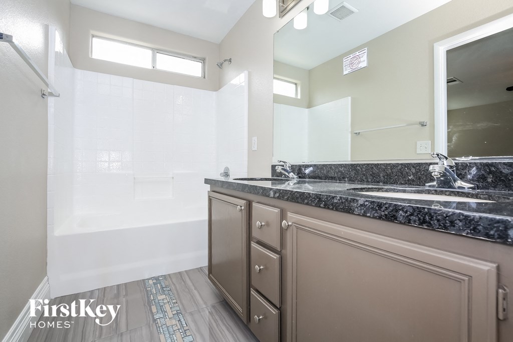 the master bathroom has dual sinks and a large mirror