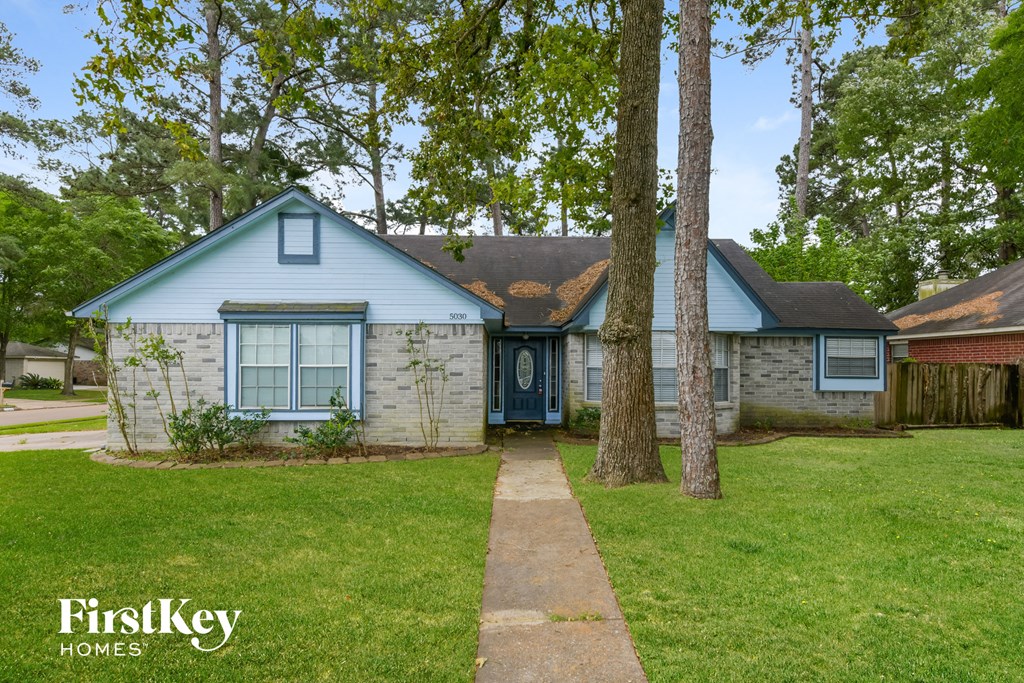 a blue and white house with a yard and trees