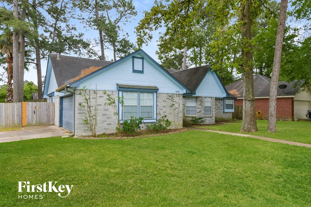 a blue and white house with a yard and trees
