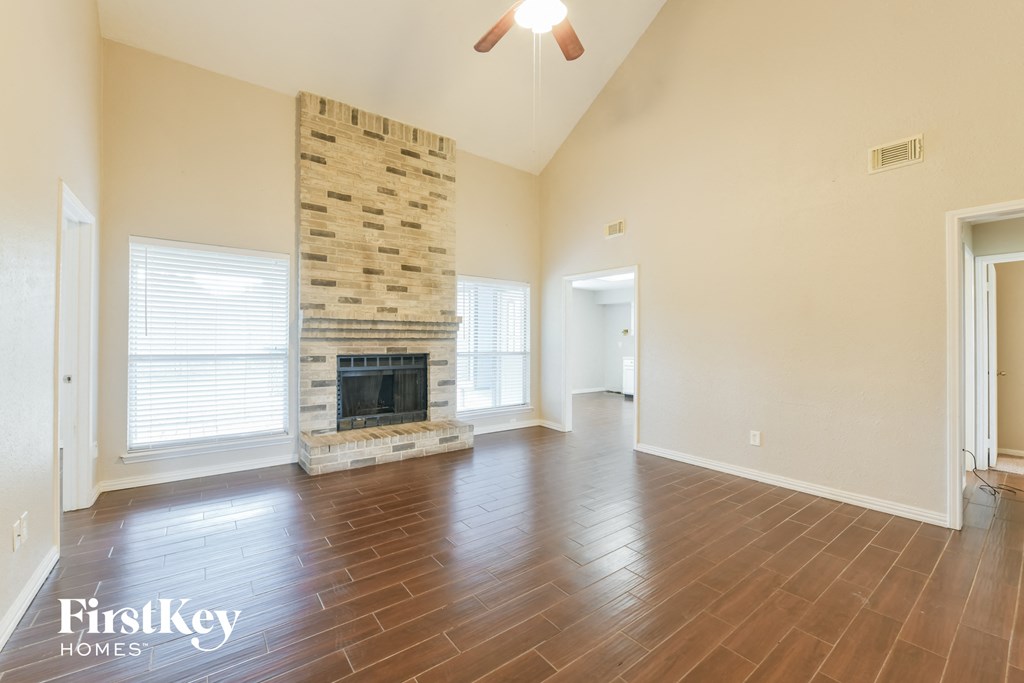 an empty living room with a fireplace and wooden floors