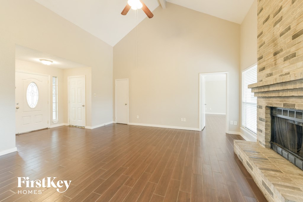 an empty living room with a fireplace and wooden floors