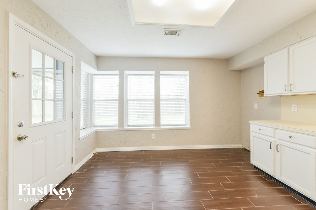 an empty kitchen with white cabinets and a window